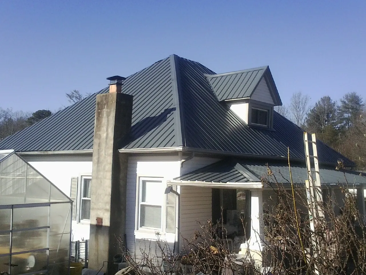Dark blue standing seam metal roof on a white farmhouse with dormer — Slate & Tile Roof Repair by Roofing Brothers in Folkston