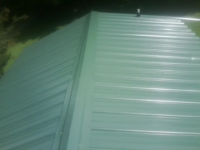 New green metal panels meeting at the ridge of a roof — Flat Roof Repair work by our crew in Folkston