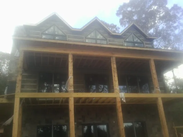 Dormers and porch framing on a large log home under construction — Roof Coating work by our crew in Folkston