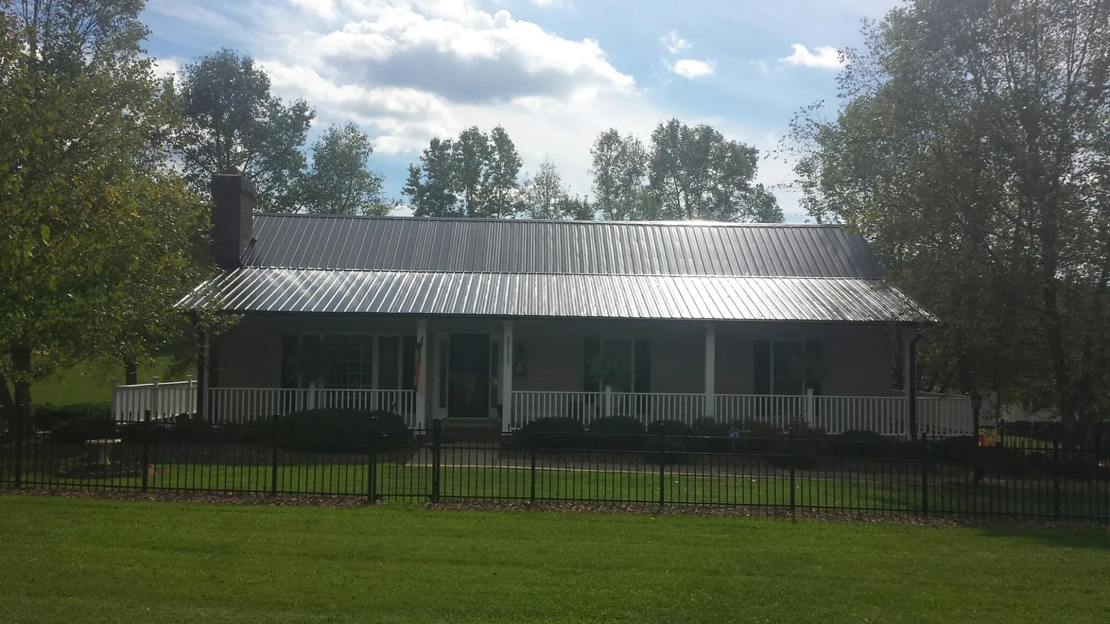 Gray metal roof on a brick ranch with a full width front porch — Gutter Guard Installation work by our crew in Folkston