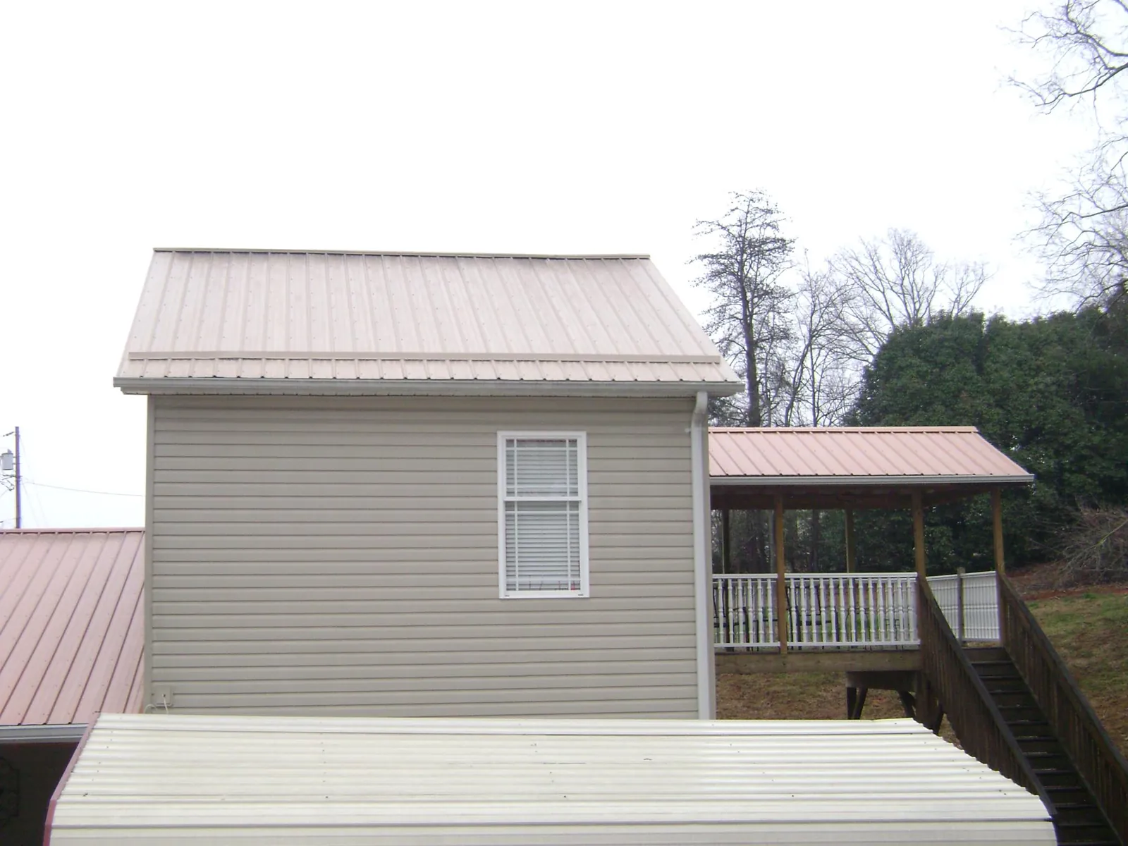 Tan metal roofs on a two story addition and attached porch, from a Roof Replacement job in Folkston