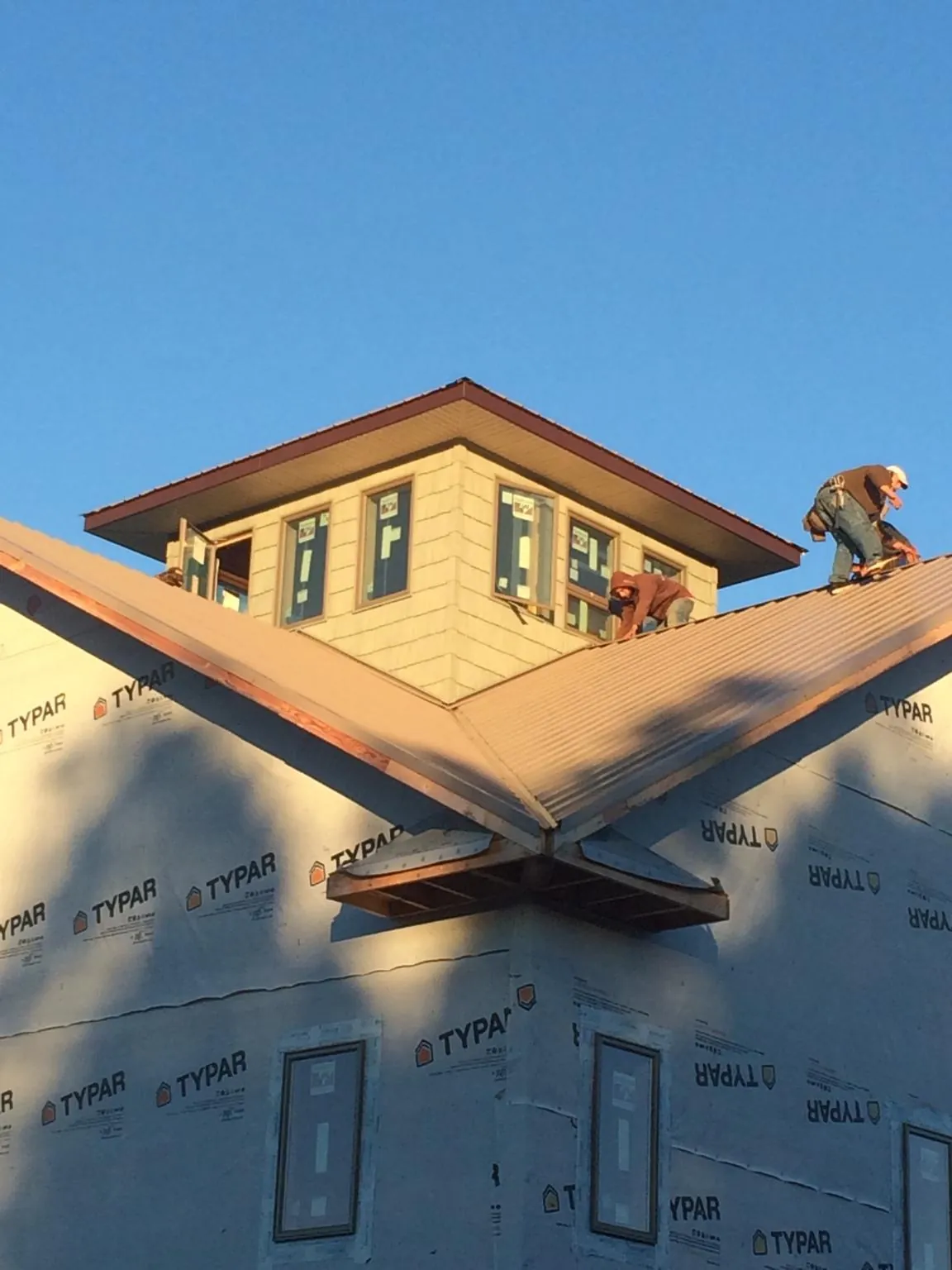 Roofers working around a rooftop cupola on a new metal roof at sunset — Roof Waterproofing in Folkston by Roofing Brothers